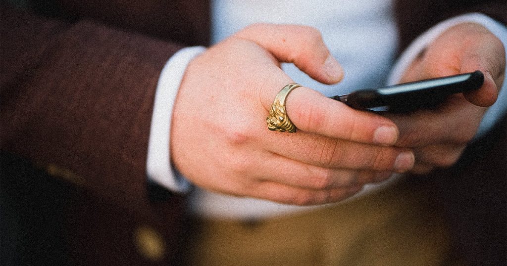 close up of man's hands with ring holding phone