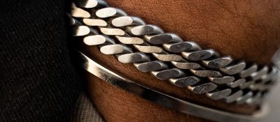 closeup of man's wrist with several silver bracelets
