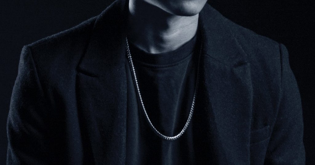 closeup of man in black wearing necklace